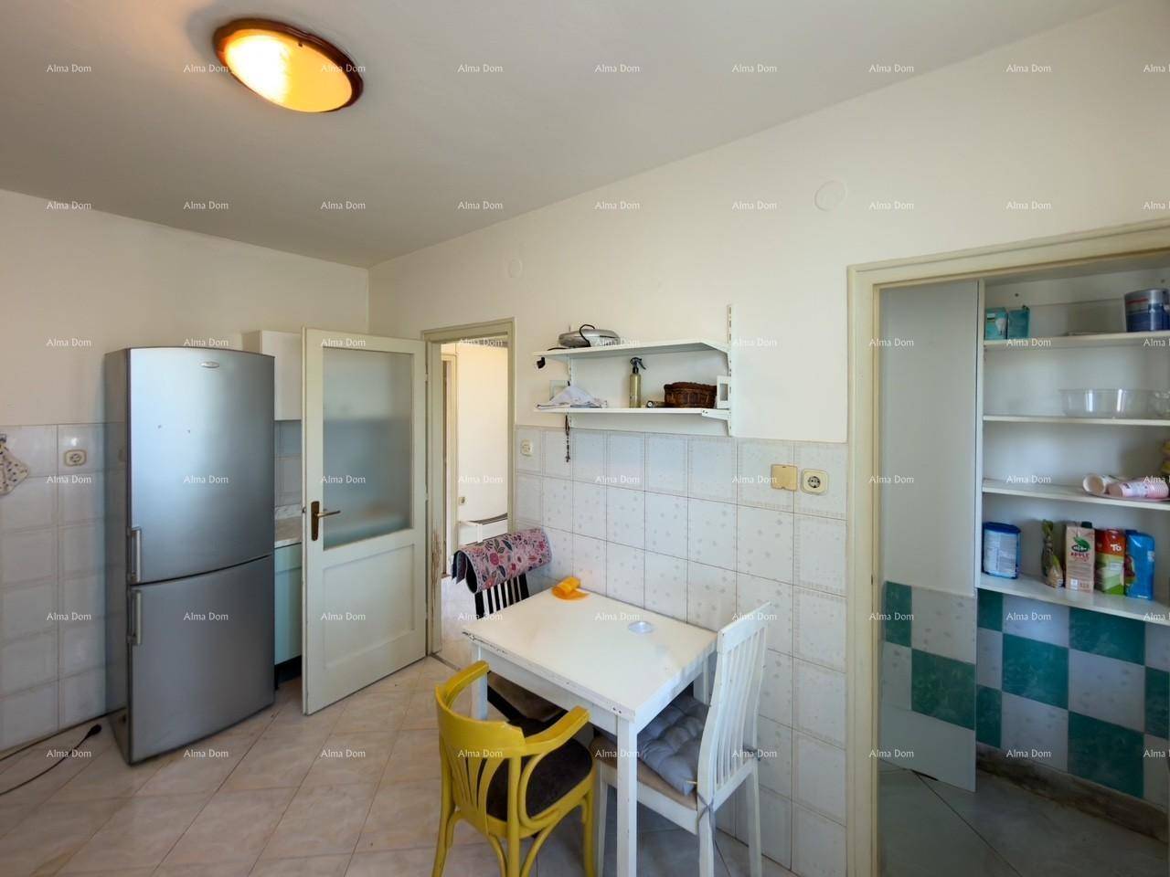 Küche mit Esstisch, Kühlschrank und Regalen, die einen Blick in die Speisekammer ermöglichen.