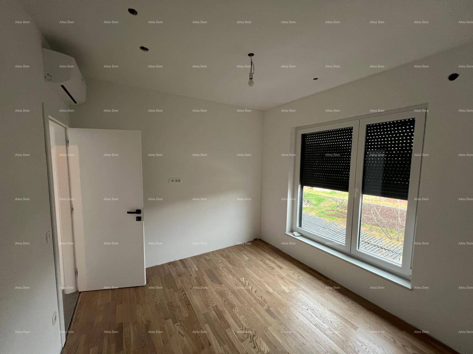 Helles Zimmer mit Parkettboden, weißen Wänden und einem Fenster mit geschlossenen Rollläden.