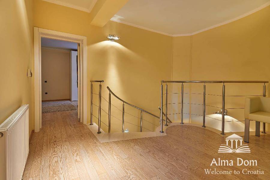 Heller Flur mit moderner Treppe, Holzboden und gelben Wänden.