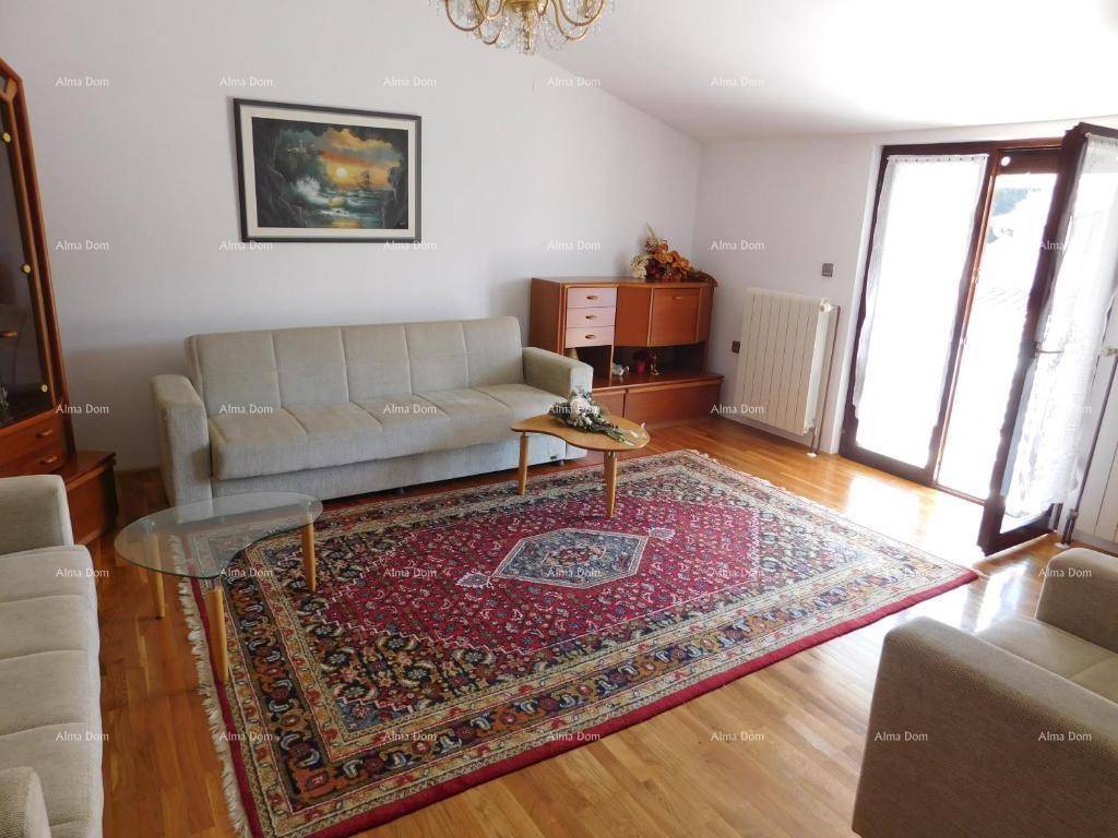 Wohnzimmer mit Holzboden, Sofa, Teppich und Zugang zu einem Balkon.