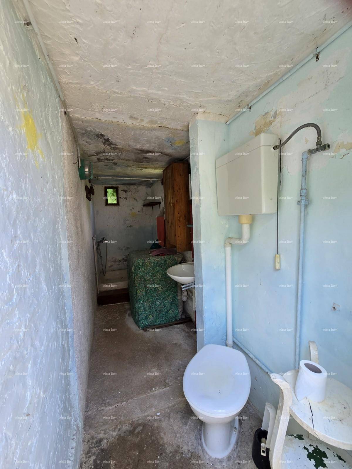 Einfaches Badezimmer mit Toilette, Waschbecken und einer kleinen Duschgelegenheit.