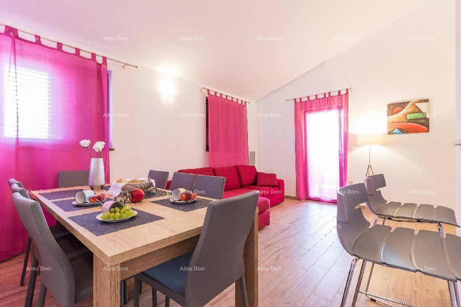 Gemütlicher Wohn-Essbereich mit rotem Sofa, Esstisch und lebhaften pinken Vorhängen.