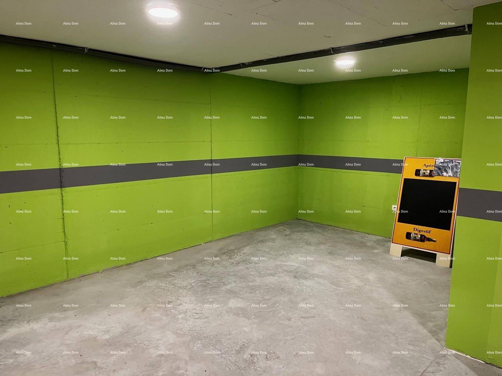 Weiterer Bereich der Tiefgarage mit grünen Wänden und einem Werbeaufsteller.