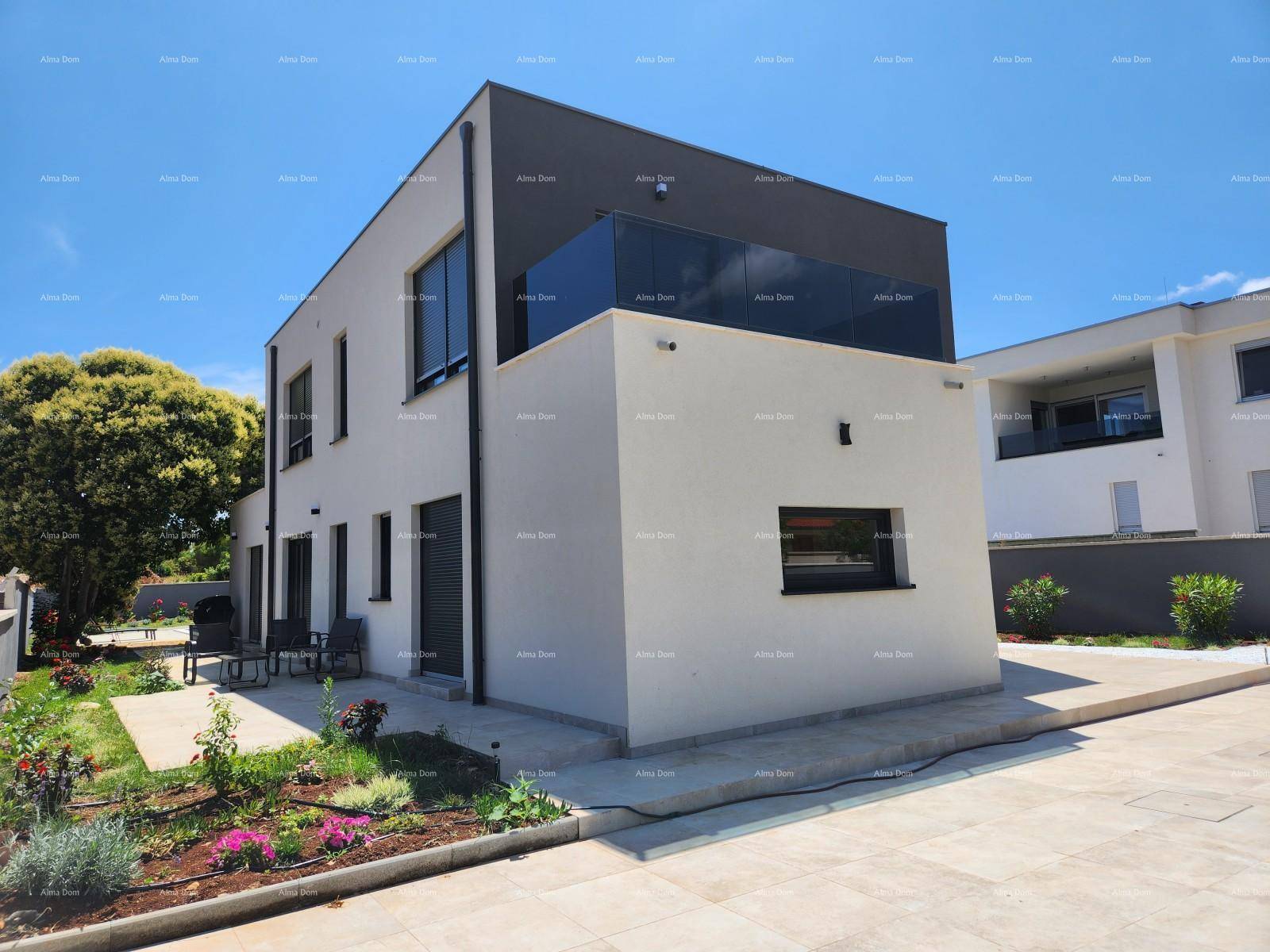 Rückansicht der modernen Villa mit kleiner Terrasse, Gartenbereich und Sitzgelegenheiten im Freien.