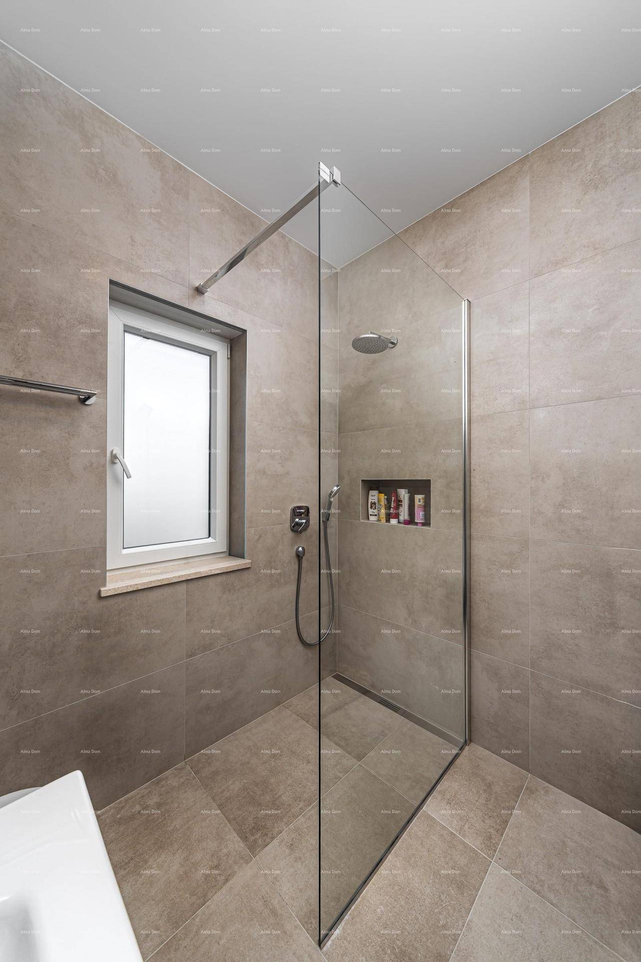 Modernes Badezimmer mit begehbarer Dusche, Regendusche und Fenster, gefliest in Grautönen.