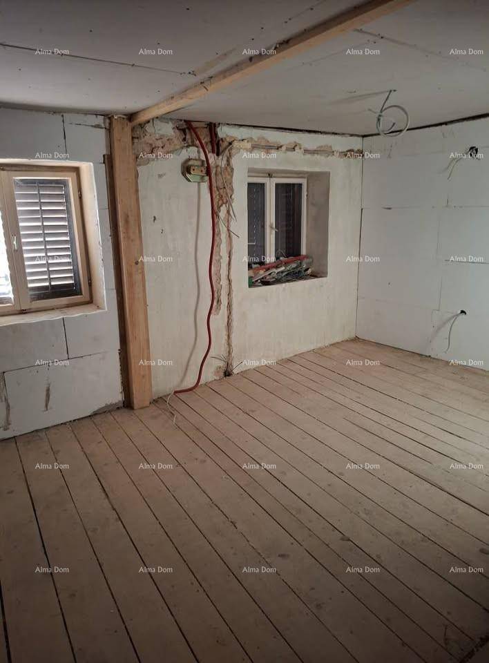 Innenraum im Rohbau mit Holzdielenboden und freiliegenden Installationen, bereit für den Ausbau.