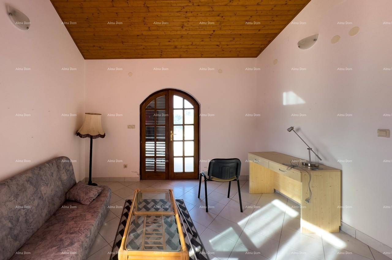 Wohnzimmer mit Sofa, Schreibtisch und einem großen Fenster, das viel Licht hereinlässt.