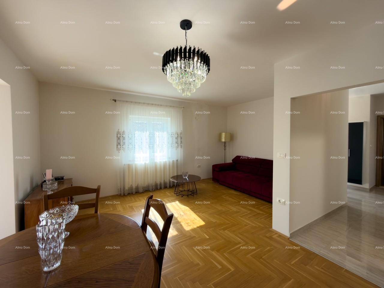 Helles Wohn- und Esszimmer mit Parkettboden, Kronleuchter und rotem Sofa.