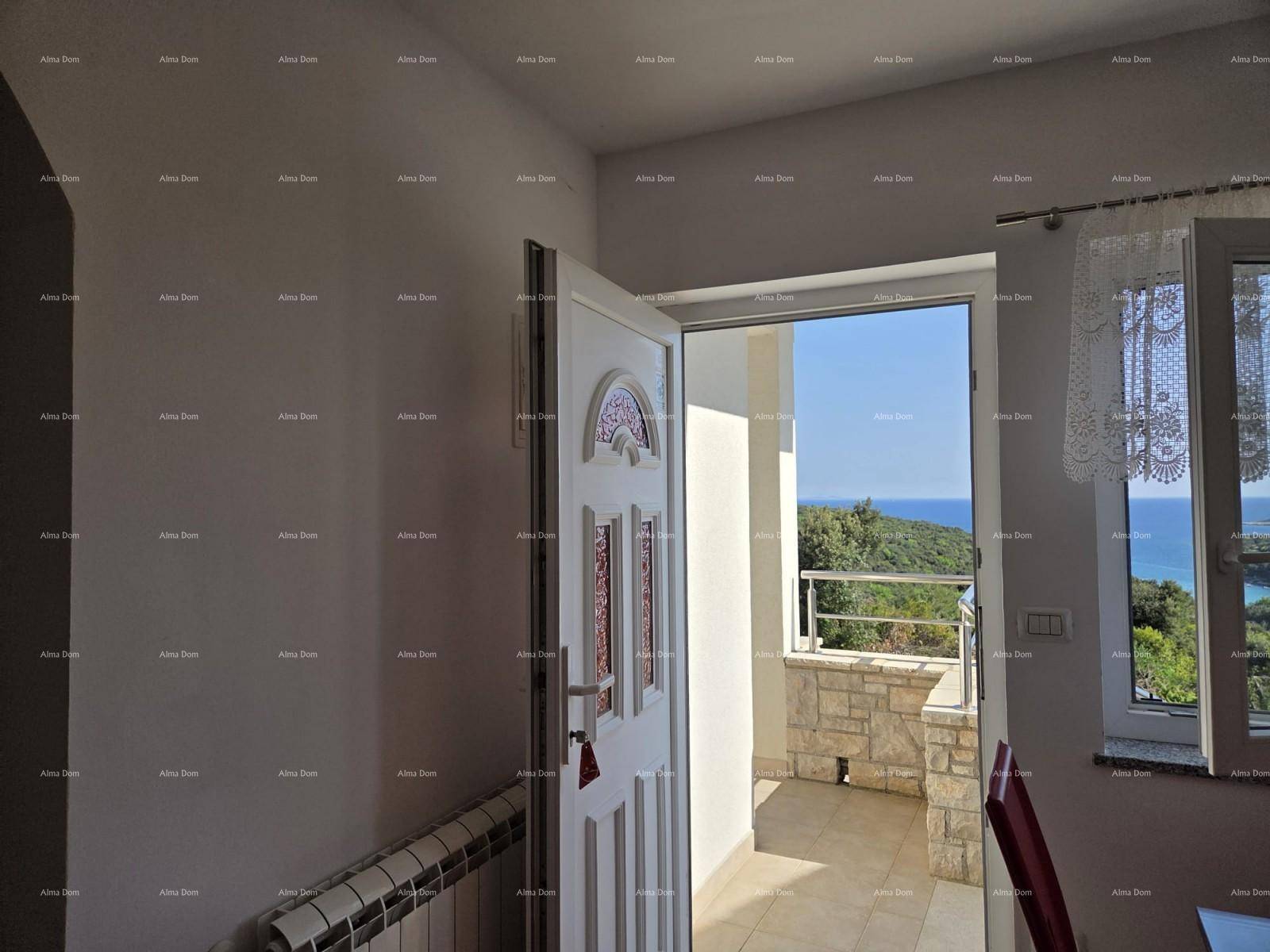 Innenbereich mit offener Tür zu einem Balkon und weitem Meerblick.
