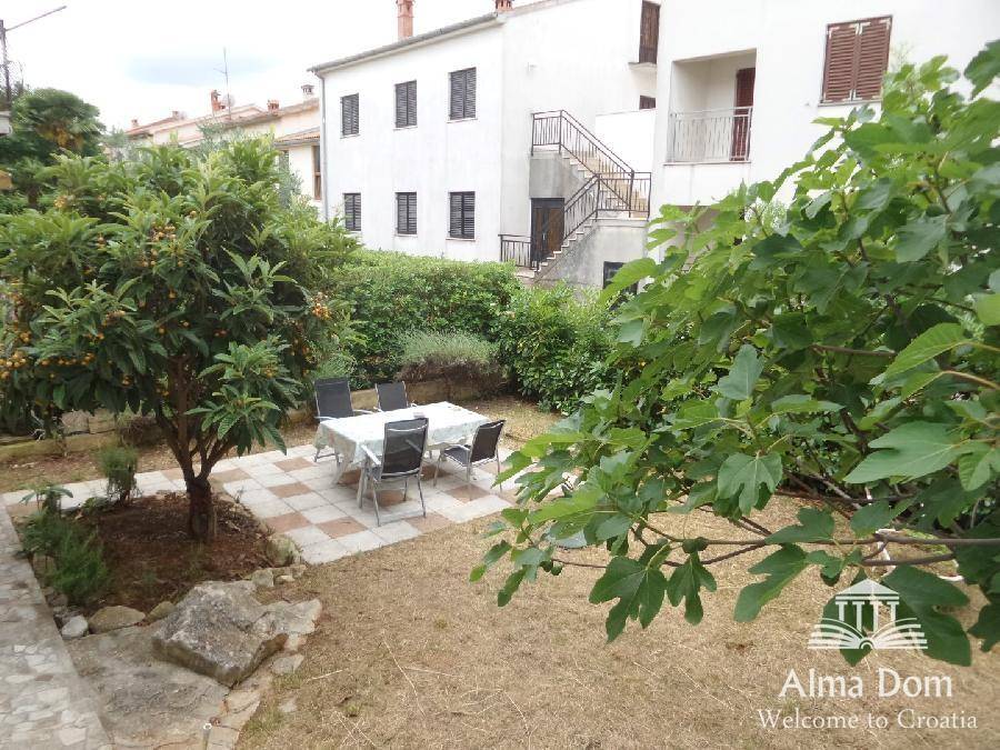 Gepflegter Gartenbereich mit Sitzgelegenheiten und Obstbäumen hinter dem Haus, ideal zum Entspannen.