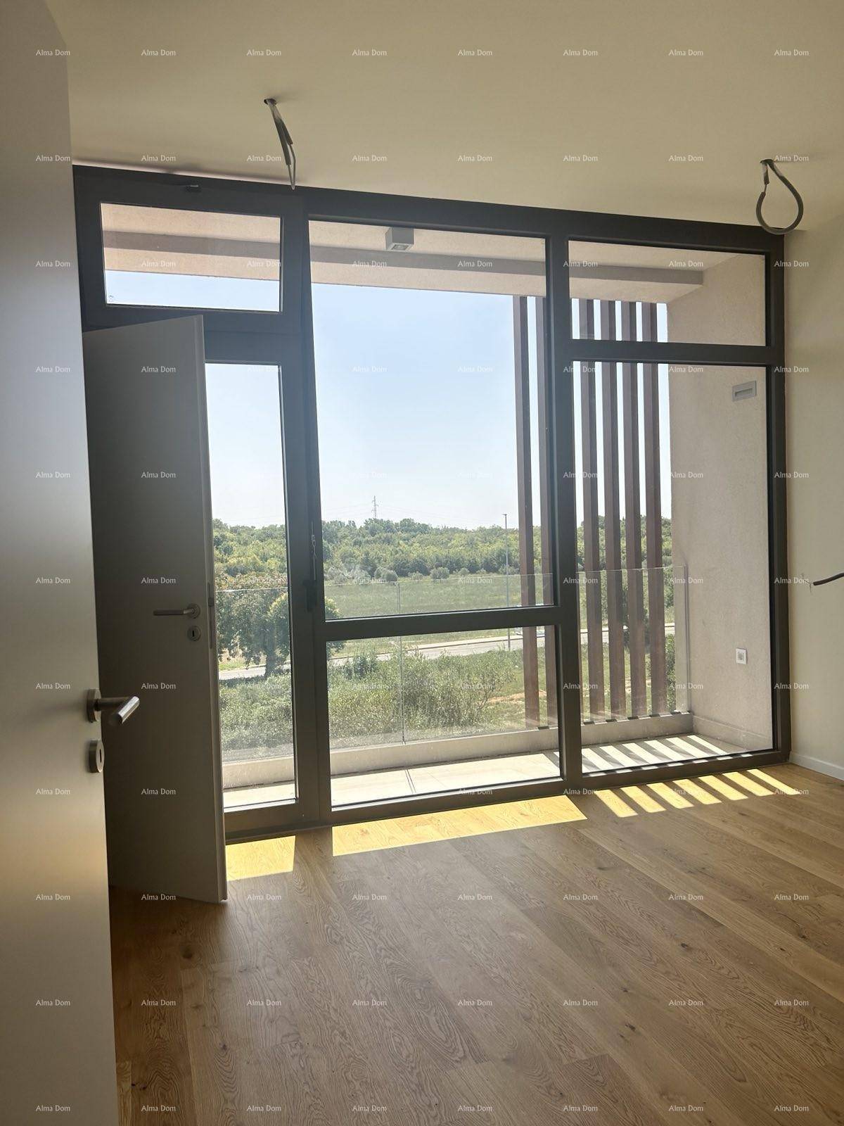 Heller Raum mit großen Fensterfronten, Holzboden und Zugang zu einem Balkon.