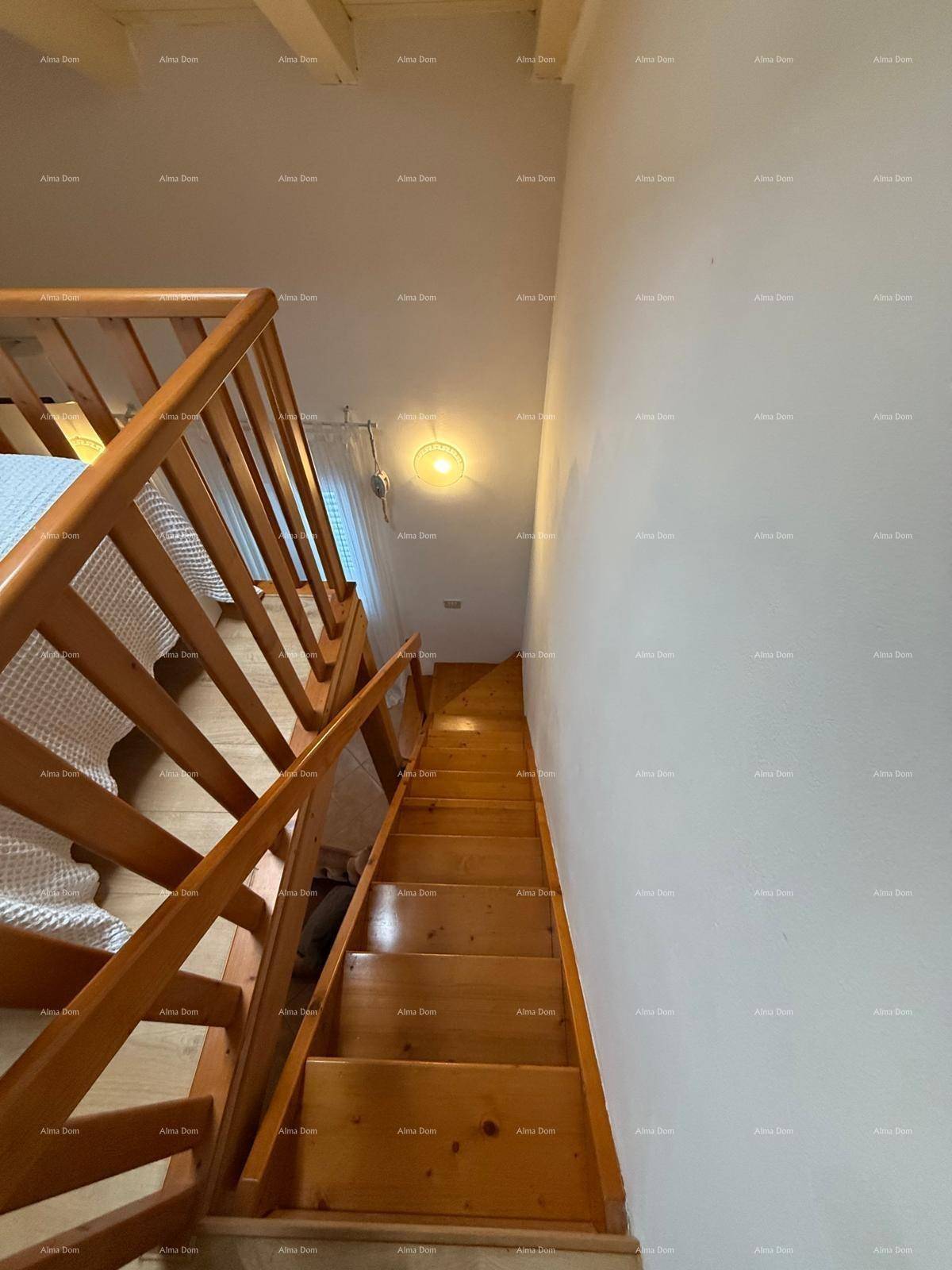 Holztreppe mit Geländer, die in das obere Stockwerk führt, mit hellen Wänden.