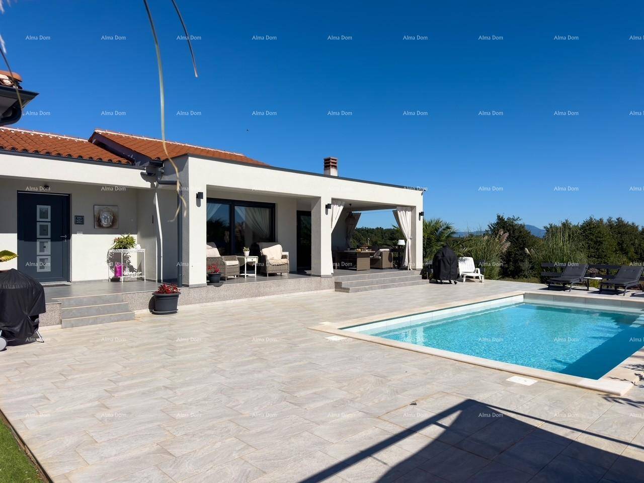 Moderne Villa mit großem Pool und weitläufiger Sonnenterrasse, umgeben von grüner Landschaft und klarem Himmel.