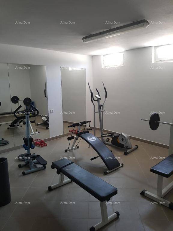 Gut ausgestatteter Fitnessraum mit verschiedenen Trainingsgeräten und Spiegelwand für das Training.