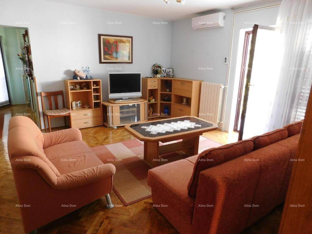 Wohnzimmer mit Holzboden, bequemen Sofas, Fernseher und Klimaanlage.