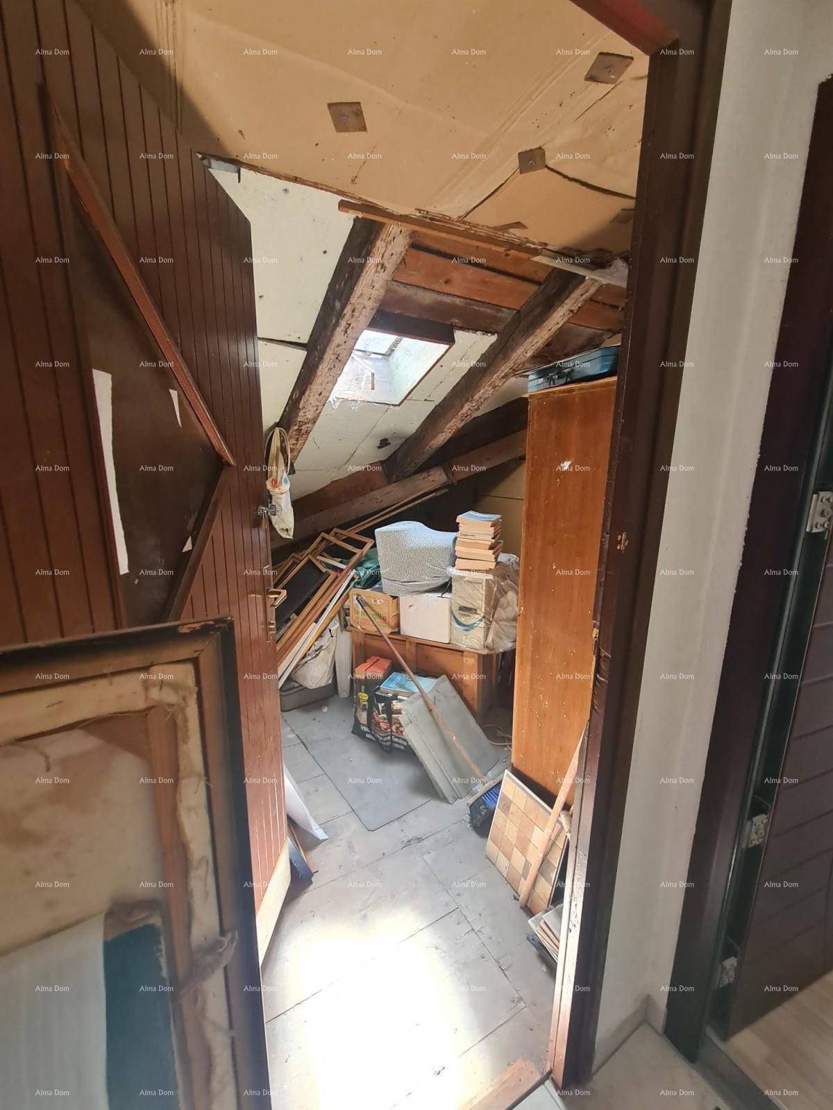 Unausgebauter Dachboden, der als Abstellraum dient, mit sichtbaren Holzbalken und einem Dachfenster.