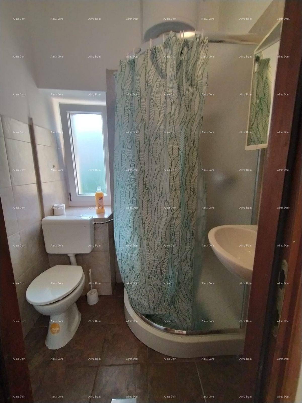 Kleines Badezimmer mit Dusche, WC und Waschbecken, ausgestattet mit einem Fenster für Tageslicht.