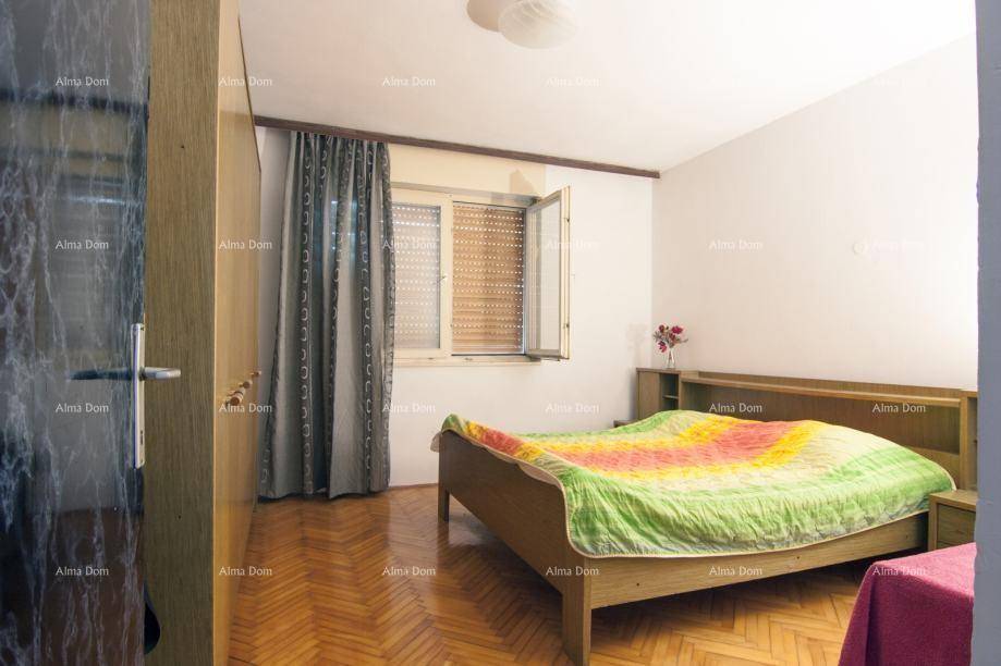 Schlafzimmer mit Holzbett, Parkettboden und einem Fenster mit Rollläden.