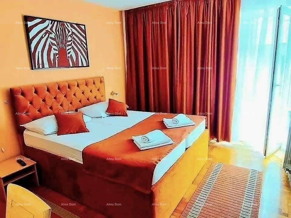 Schlafzimmer mit großem Doppelbett, gepolstertem Kopfteil und roten Vorhängen vor einem Fenster.