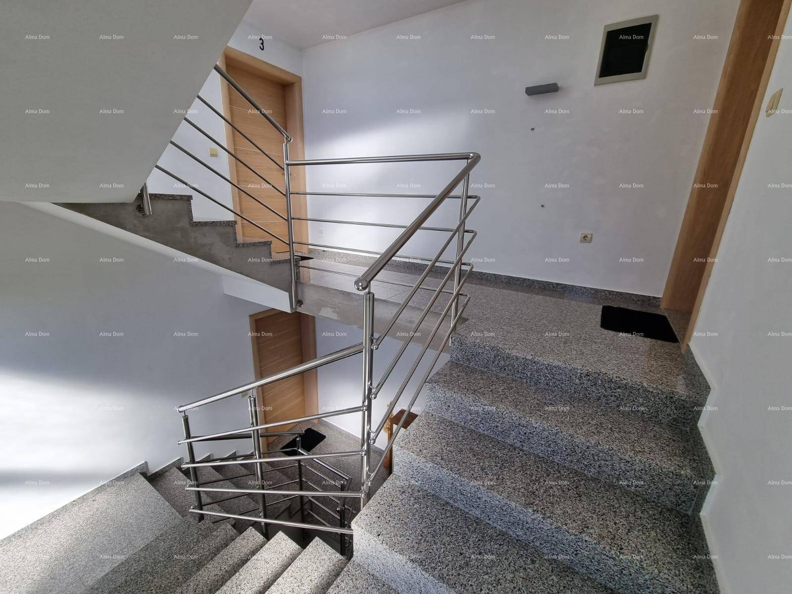 Treppenhaus mit Granitstufen und modernen Edelstahlgeländern, das die Etagen verbindet.