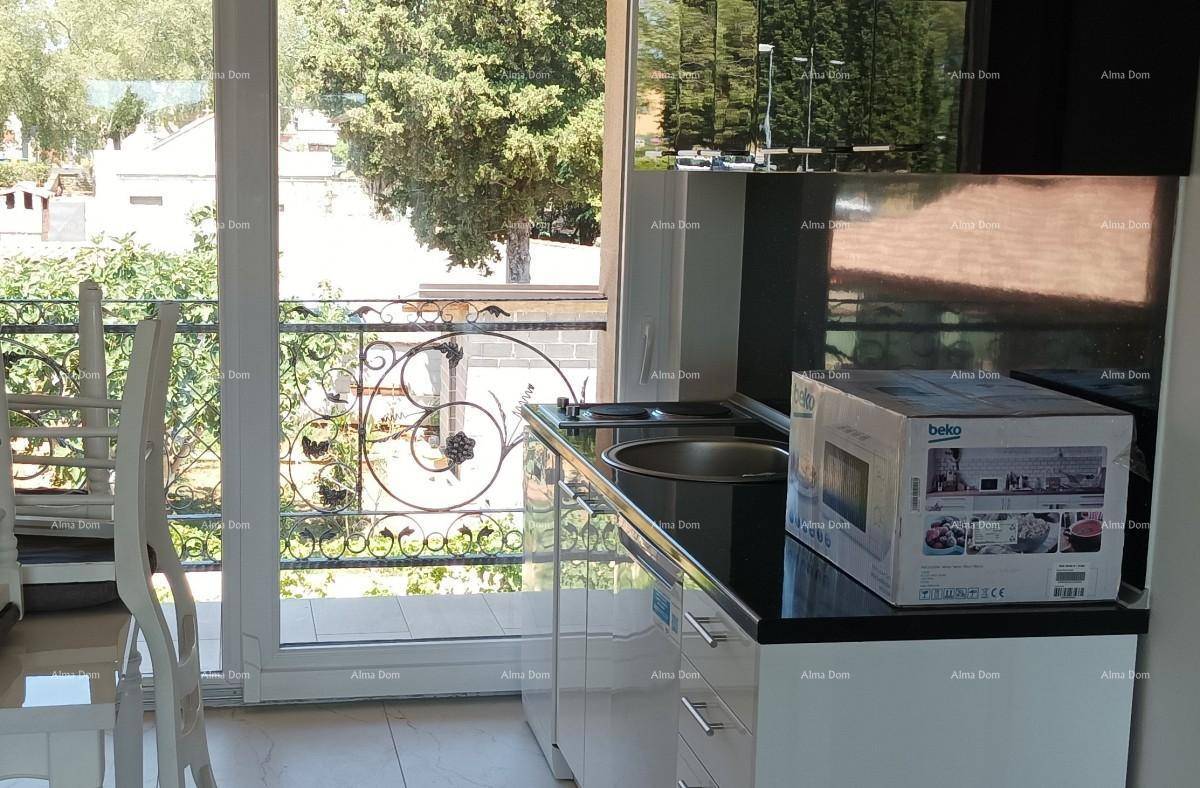 Kleine Küche mit modernen weißen Schränken, schwarzer Arbeitsplatte und Blick ins Grüne.