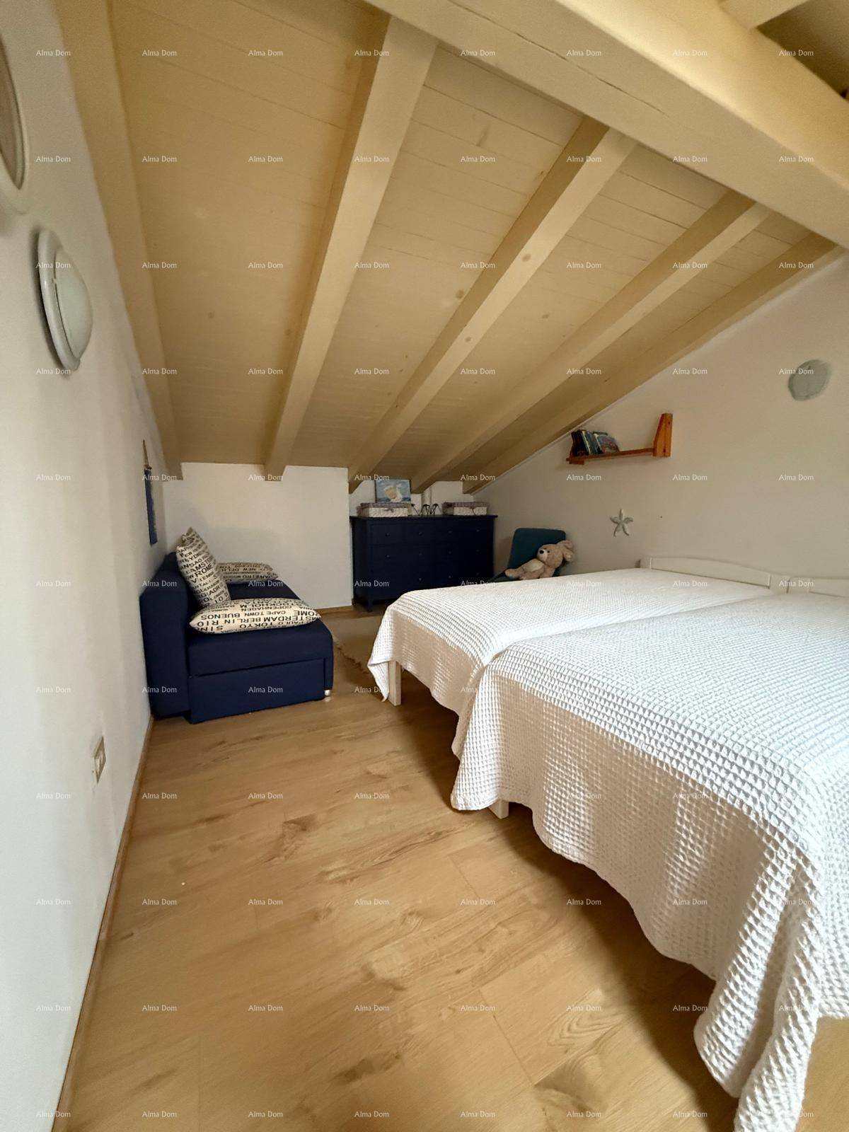 Geräumiges Dachgeschoss-Schlafzimmer mit Holzbalkendecke und Holzboden, eingerichtet mit einem Sofa.