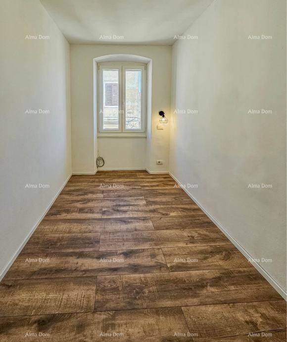 Schmaler Raum mit Holzboden und einem Fenster, vielseitig nutzbar als Büro oder Flur.