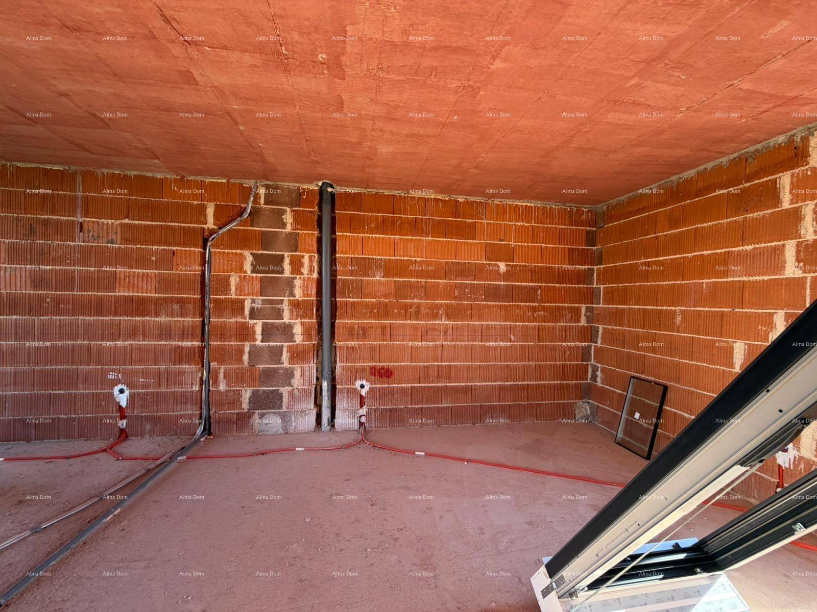 Innenraum im Rohbau mit sichtbaren Wasserleitungen und einem Fensterrahmen.