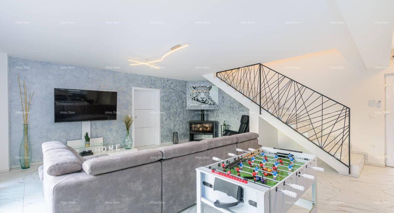 Geräumiges Wohnzimmer mit Ecksofa, Kaminofen, Tischfußball und moderner Treppe.