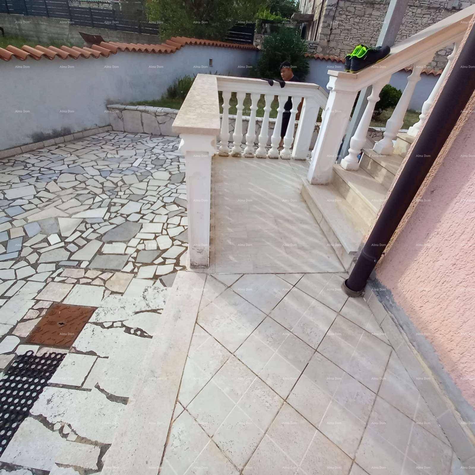 Außentreppe, die zu einem gepflasterten Bereich führt, umgeben von einer Balustrade.