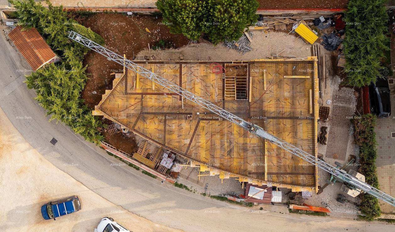 Draufsicht auf die Baustelle mit einem Kranarm über der Bewehrung der Betondecke und umliegenden Straßen.