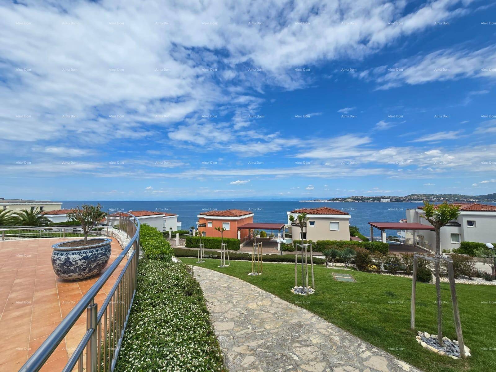 Gepflegter Gartenbereich mit Rasenfläche, Gehwegen und weitem Blick auf das Meer und die Küste.