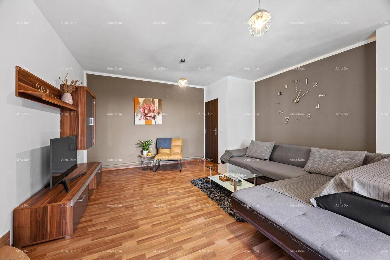 Gemütliches Wohnzimmer mit großem Ecksofa, Holzboden und einer modernen Wanduhr als Dekoration.