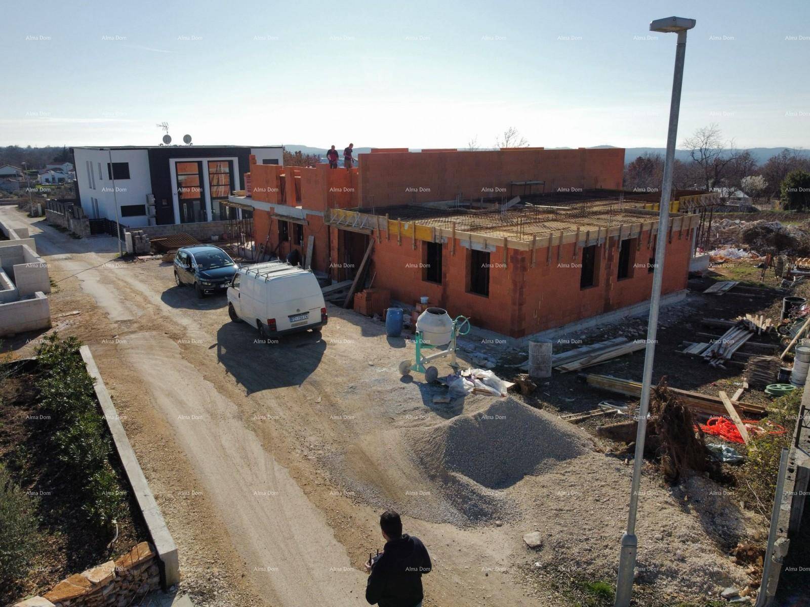 Baustelle mit unbefestigter Zufahrt, Baufahrzeugen und dem Rohbau eines neuen Wohnhauses.
