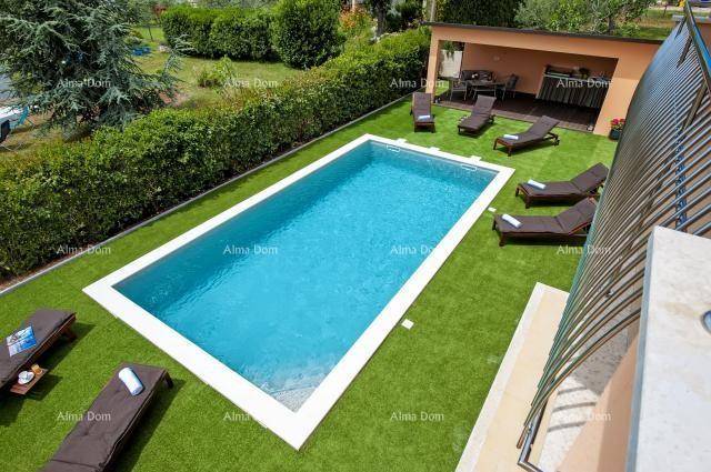 Rechteckiger Swimmingpool umgeben von gepflegtem Rasen und Sonnenliegen im Gartenbereich.