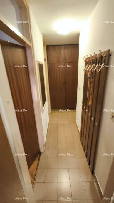 Langer Flur mit Fliesenboden, großem Holzschrank und praktischer Garderobe.