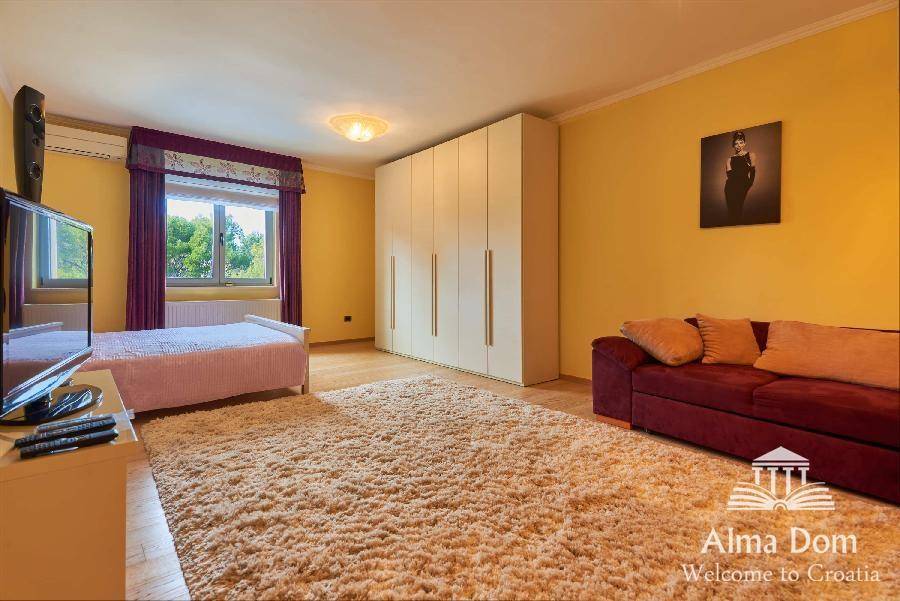 Geräumiges Schlafzimmer mit Holzboden, Teppich, gelben Wänden und großem Kleiderschrank.