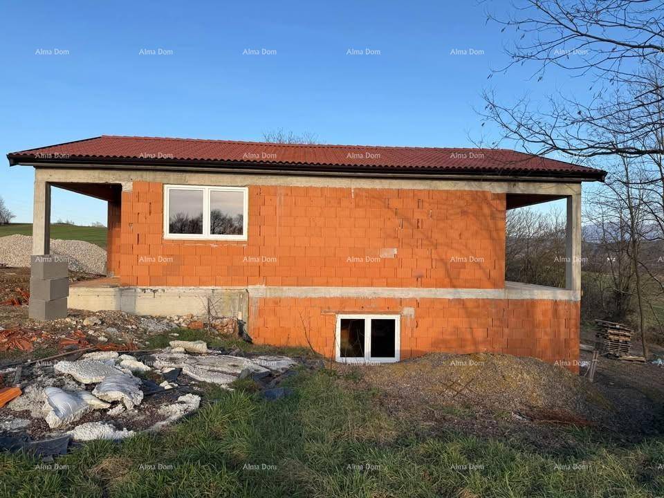 Seitenansicht des Rohbaus mit rotem Ziegeldach und unfertiger Fassade in ländlicher Umgebung.