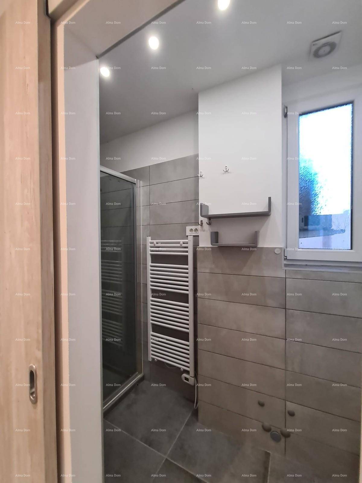 Modernes Badezimmer mit Duschkabine, grauen Fliesen, beheiztem Handtuchhalter und Fenster.