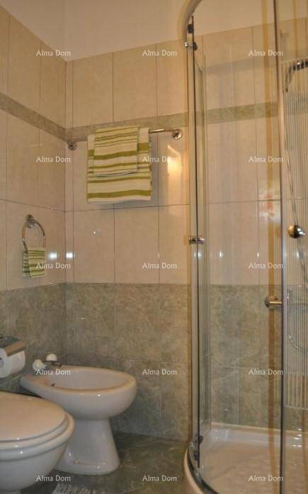 Badezimmer mit Duschkabine, Bidet und hellen Fliesen an Wänden und Boden.