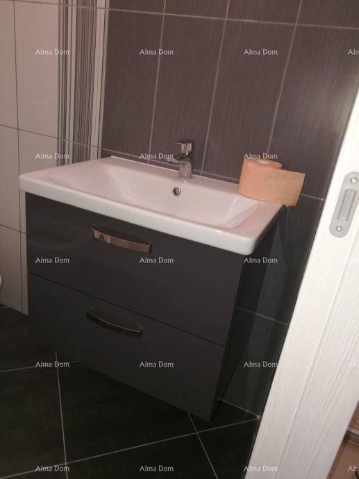 Modernes Badezimmer mit Waschtischunterschrank und dunklen Fliesen an Wand und Boden.