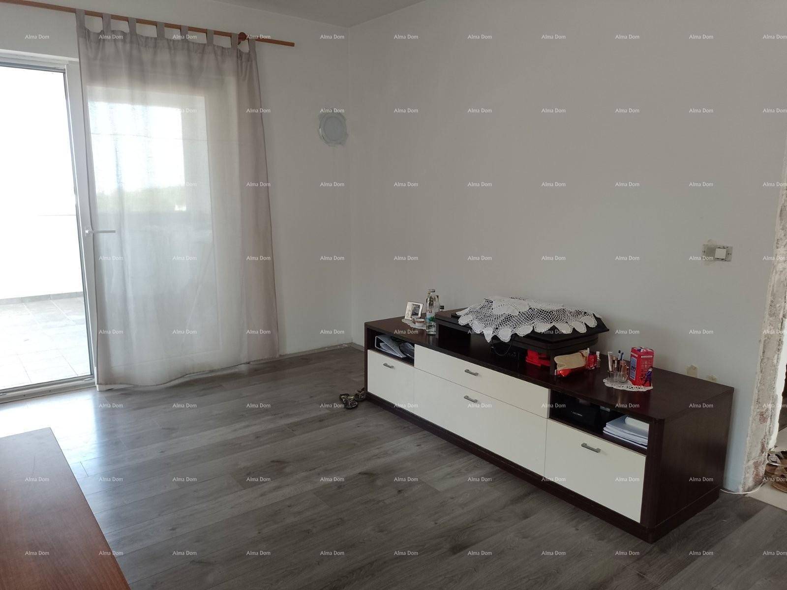 Wohnzimmer mit Laminatboden, TV-Möbel und Zugang zu einem sonnigen Außenbereich.