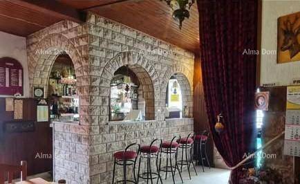 Detailansicht der rustikalen Bar mit Steinbögen und roten Barhockern unter einer Holzbalkendecke.