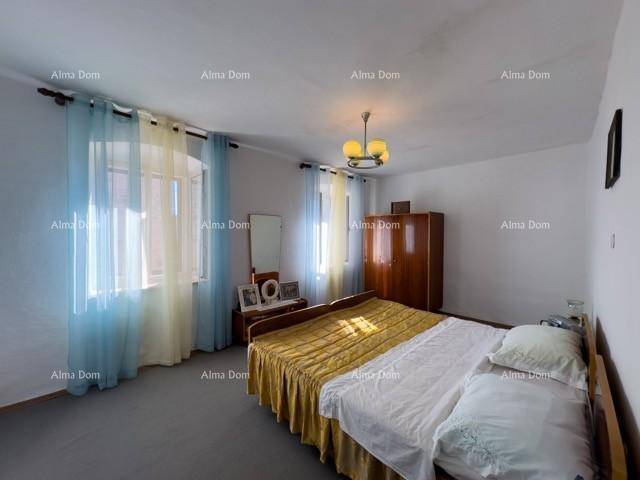 Schlafzimmer mit Doppelbett, Kleiderschrank und Fenstern mit farbigen Vorhängen in einem älteren Stil.