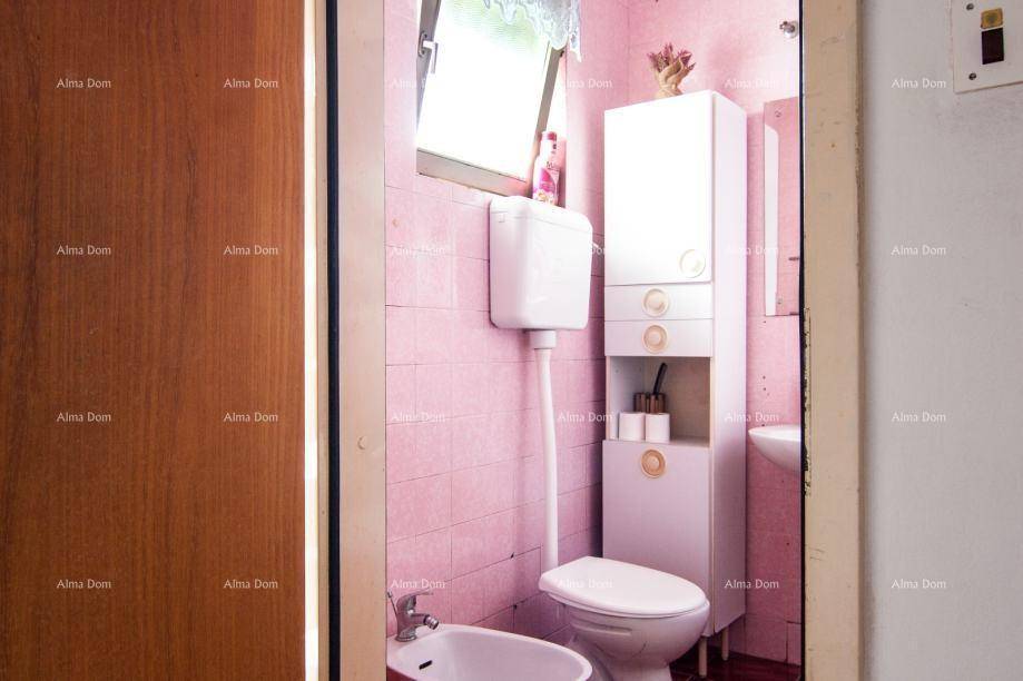 Badezimmer mit rosa Fliesen, Toilette, Bidet und einem Fenster.