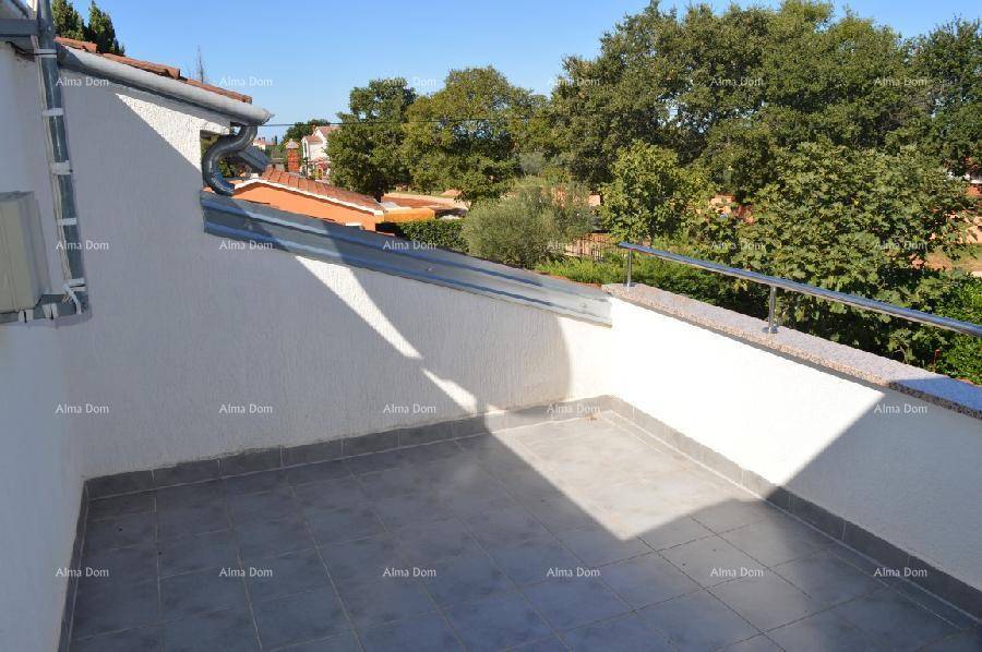 Helle, geflieste Terrasse mit Metallgeländer und Blick auf die Umgebung unter blauem Himmel.