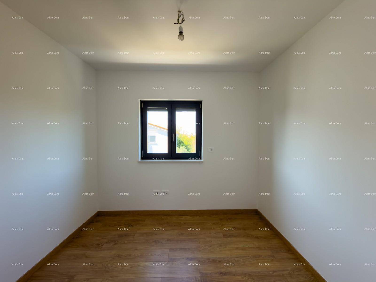 Helles Schlafzimmer mit Holzfußboden und einem Fenster mit Blick ins Grüne.