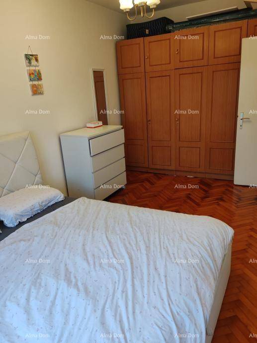 Schlafzimmer mit großem Kleiderschrank, Doppelbett und traditionellem Parkettboden.