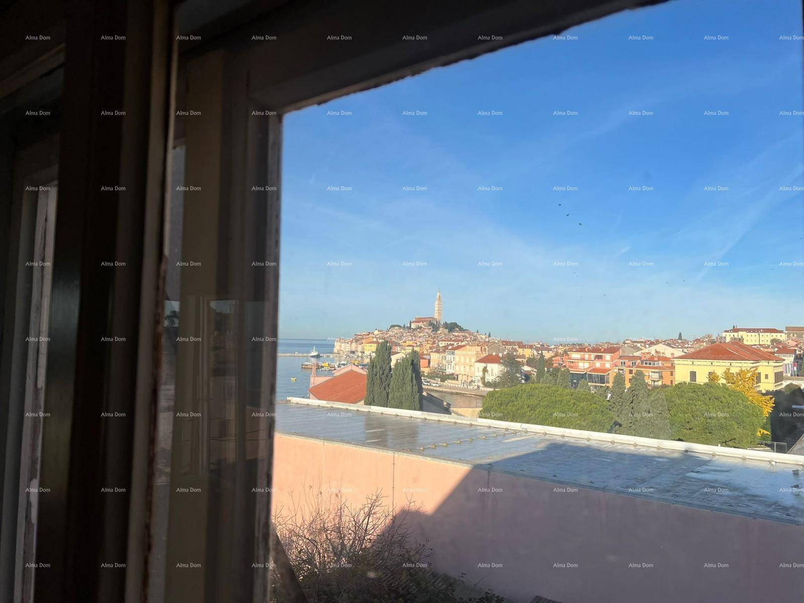 Blick durch ein Fenster auf eine malerische historische Stadt am Meer mit charakteristischen roten Dächern.