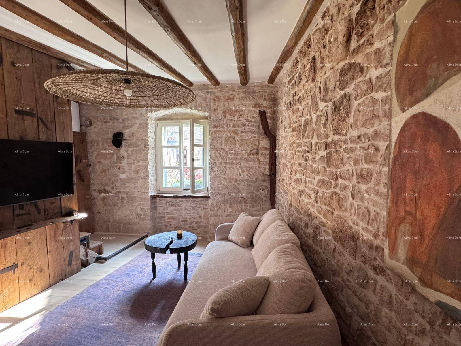 Helles Wohnzimmer mit Steinwänden, Holzbalken und einem kleinen Fenster, das Tageslicht hereinlässt.